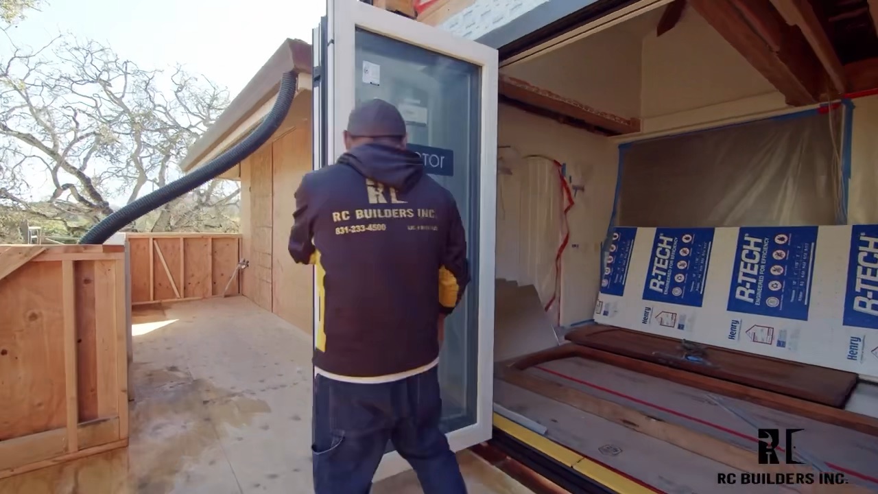 Glass door installation RC Builders crew installing a large folding glass door in a framed home addition