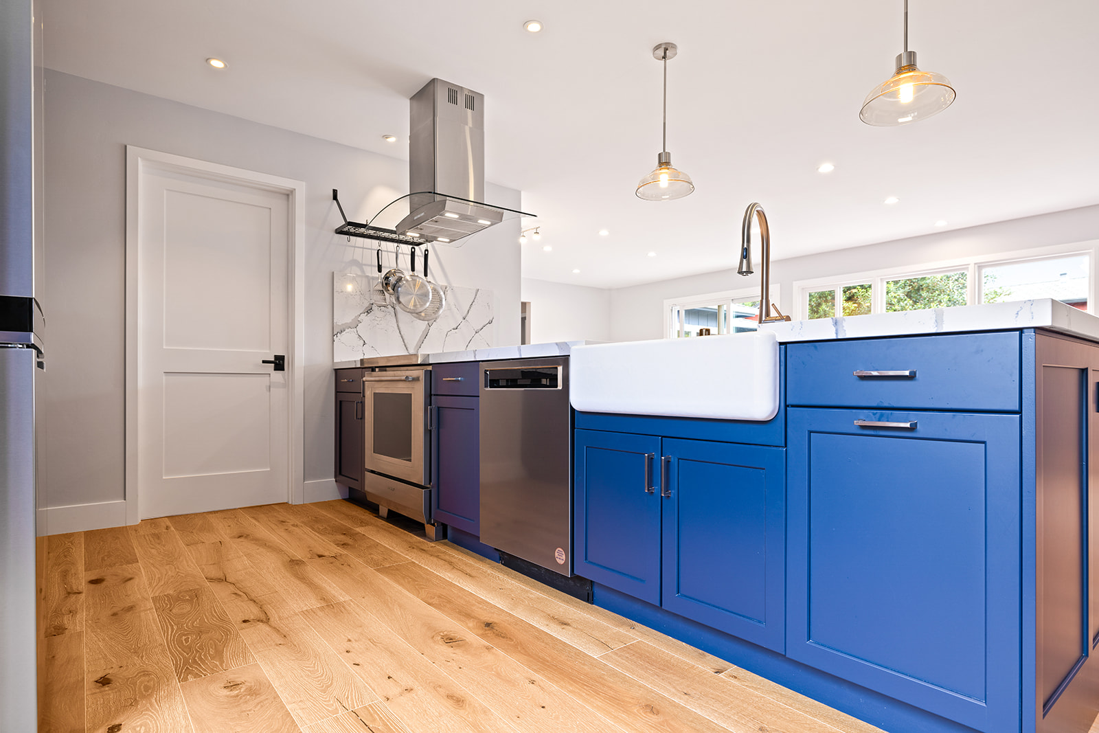 Farmhouse sink and white oak flooring Kitchen remodel with farmhouse apron sink, navy cabinets, and wide-plank white oak flooring