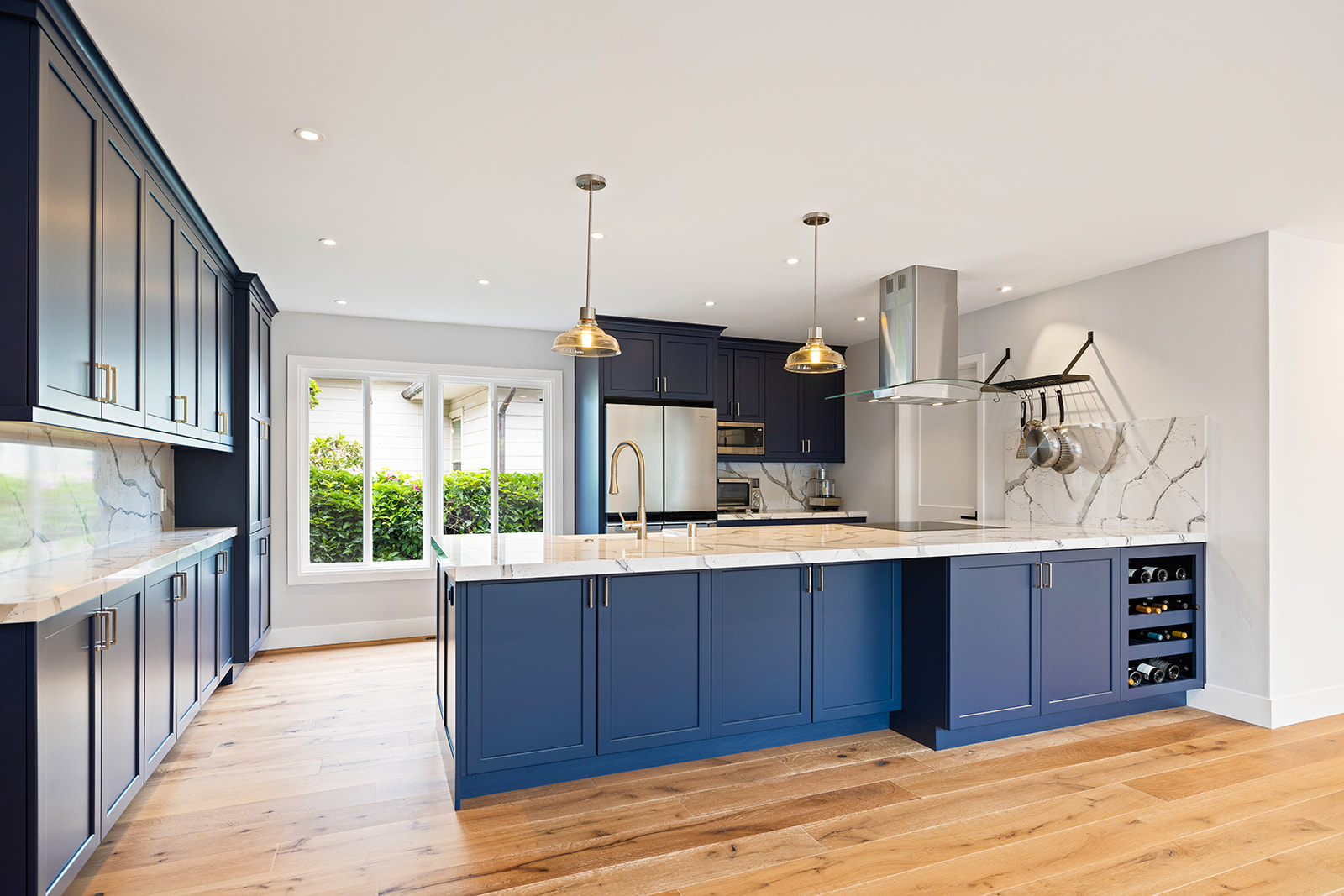 Open kitchen remodel with oak floors Open-concept kitchen remodel with navy island, pendant lighting, and white oak floors