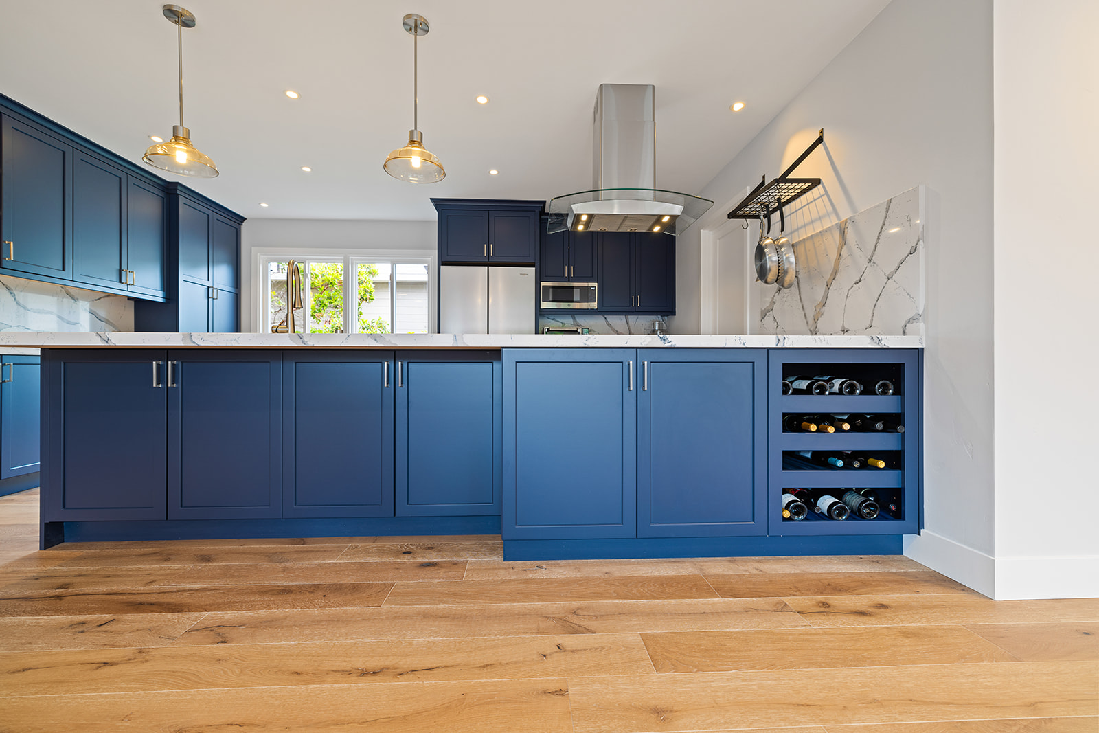 Custom cabinetry with built-in wine rack Custom navy kitchen cabinets with built-in wine rack and marble-look quartz backsplash