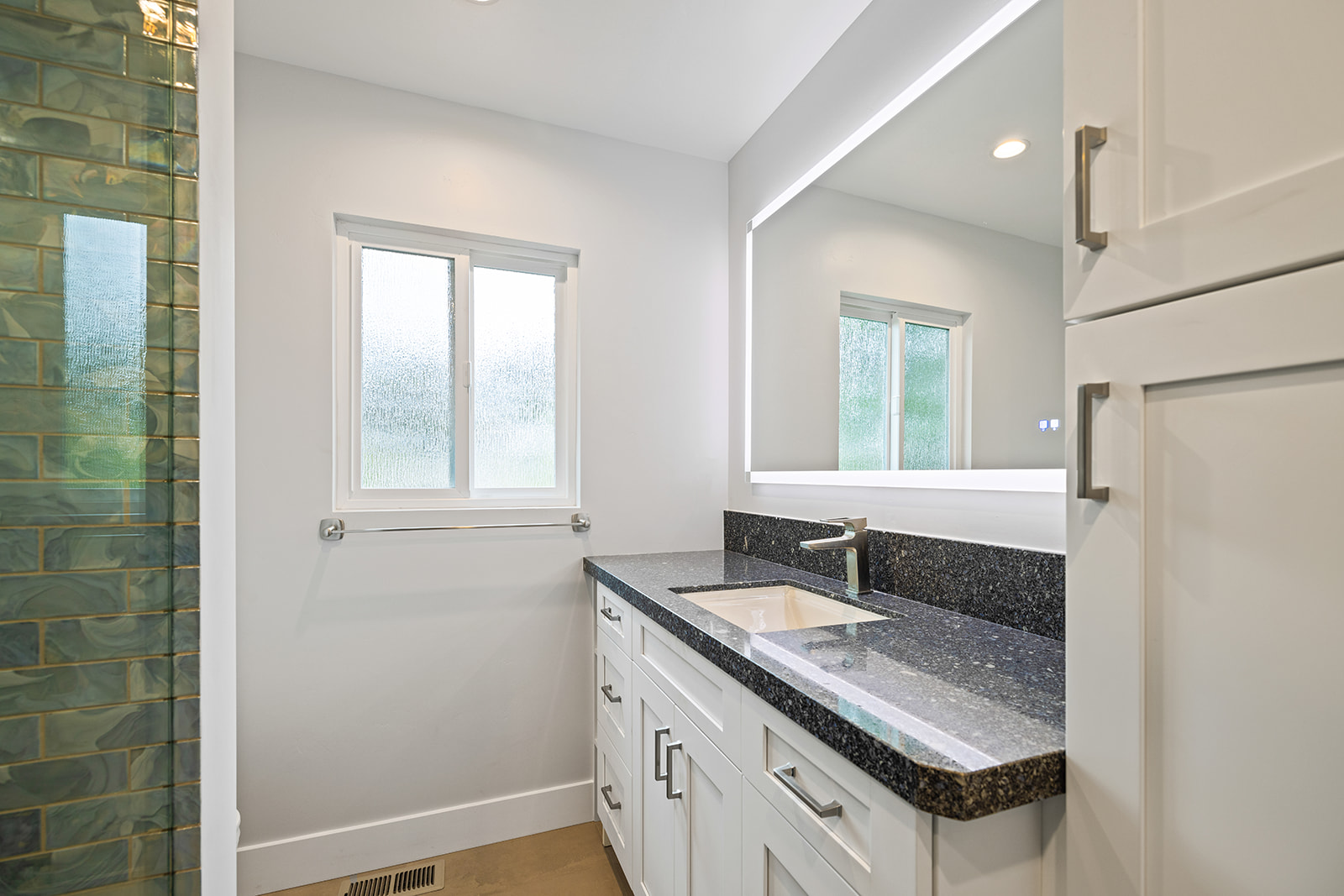 Cabinetry with granite counter and glass tile Custom white cabinetry with granite countertop and green glass tile backsplash