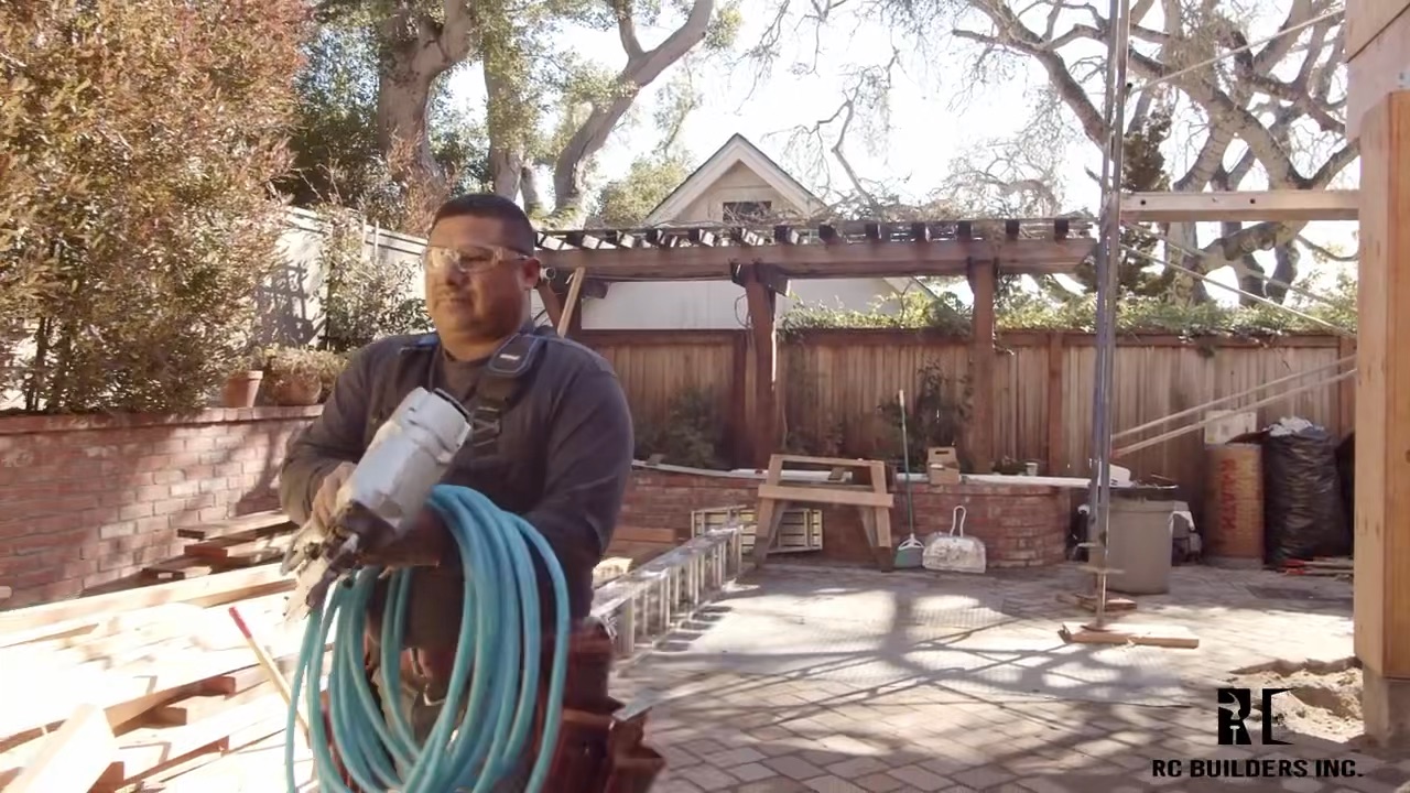 Outdoor living construction RC Builders crew member working on an outdoor living project with pergola and brick patio