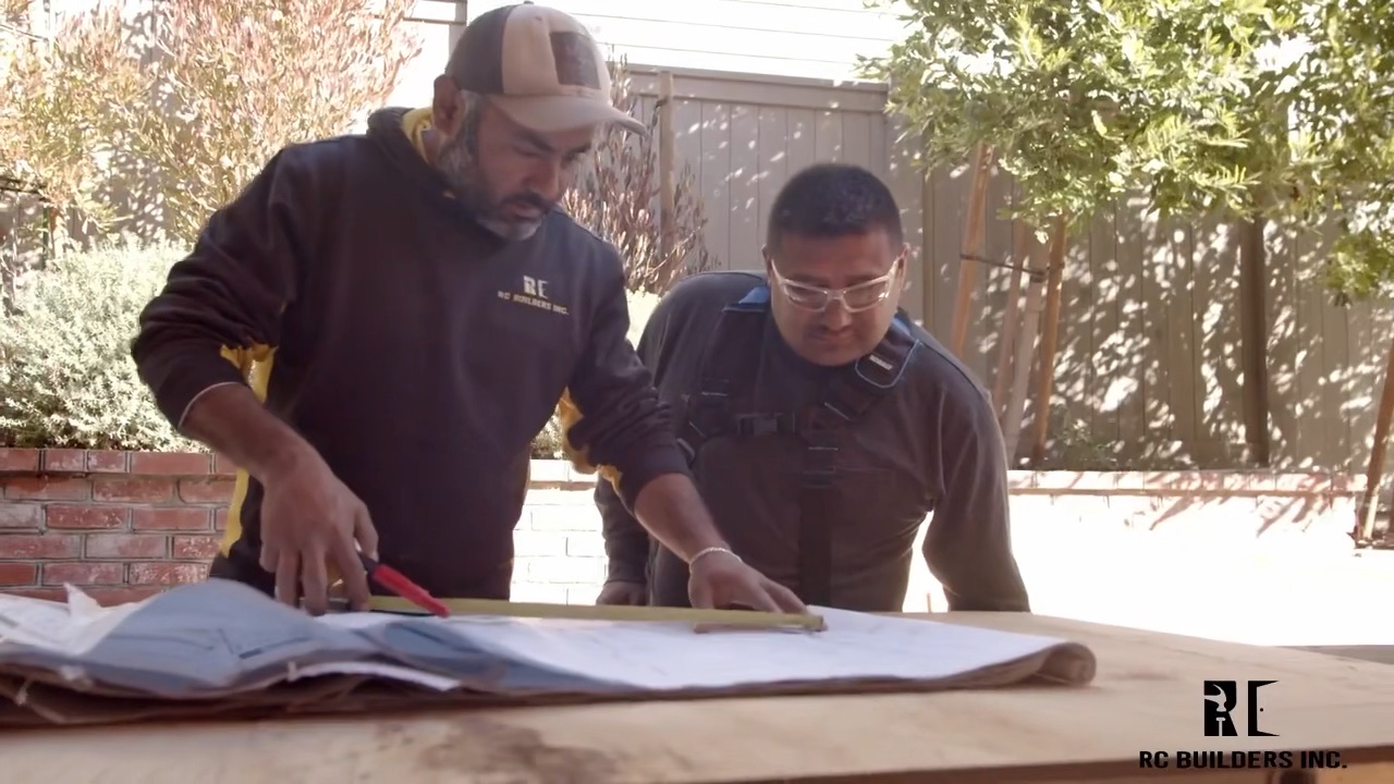 RC Builders crew members reviewing construction plans on the job site