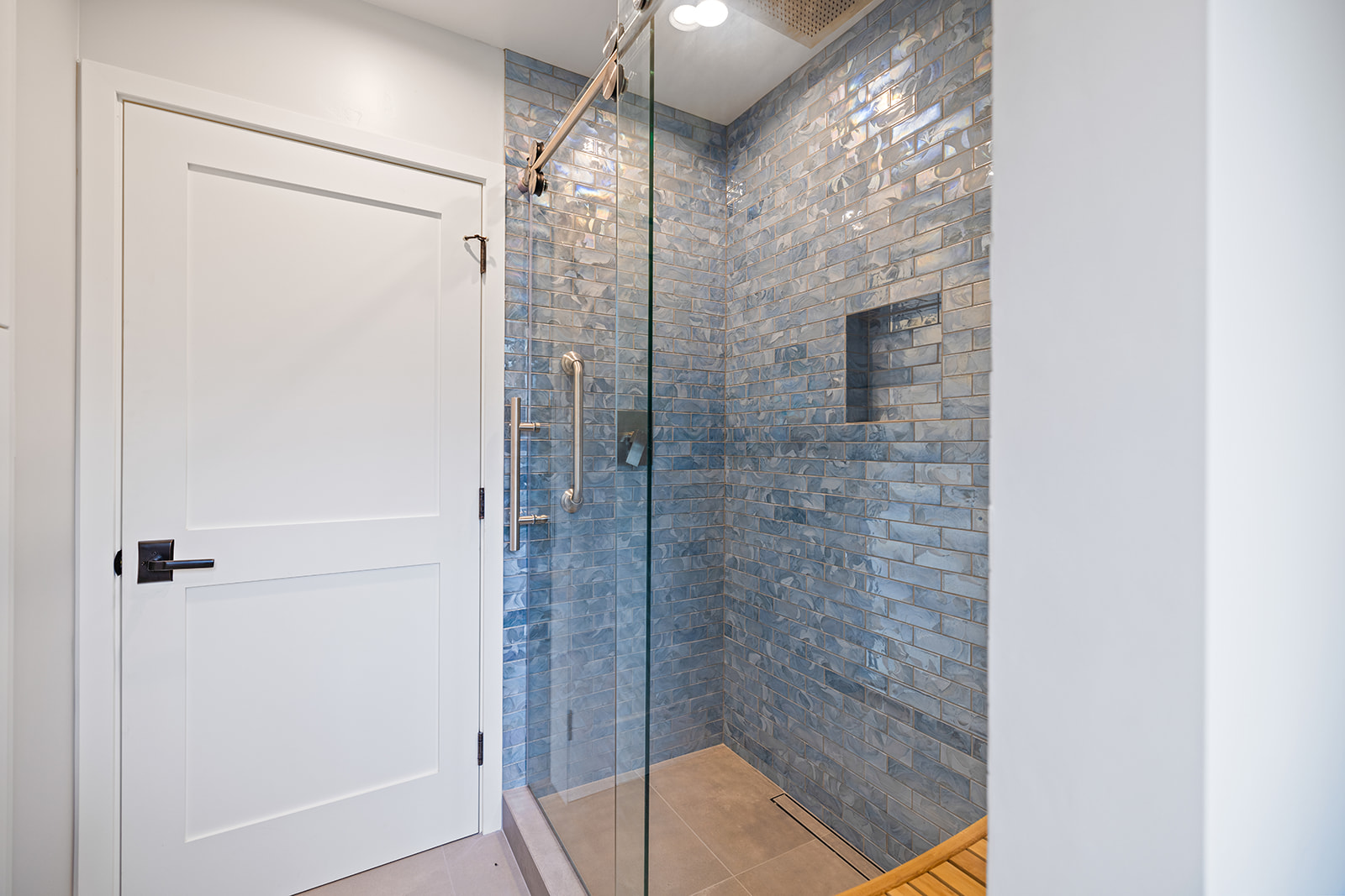 Custom shower with blue handmade tile Custom tiled walk-in shower with blue handmade-look subway tile and frameless glass enclosure